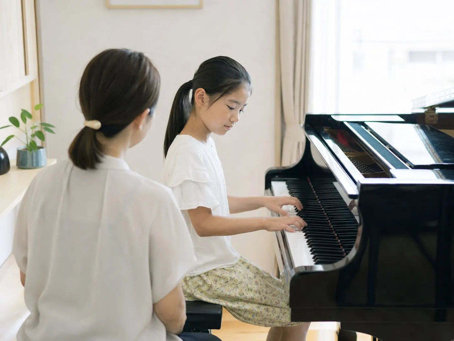 講師とピアノを学ぶ子ども